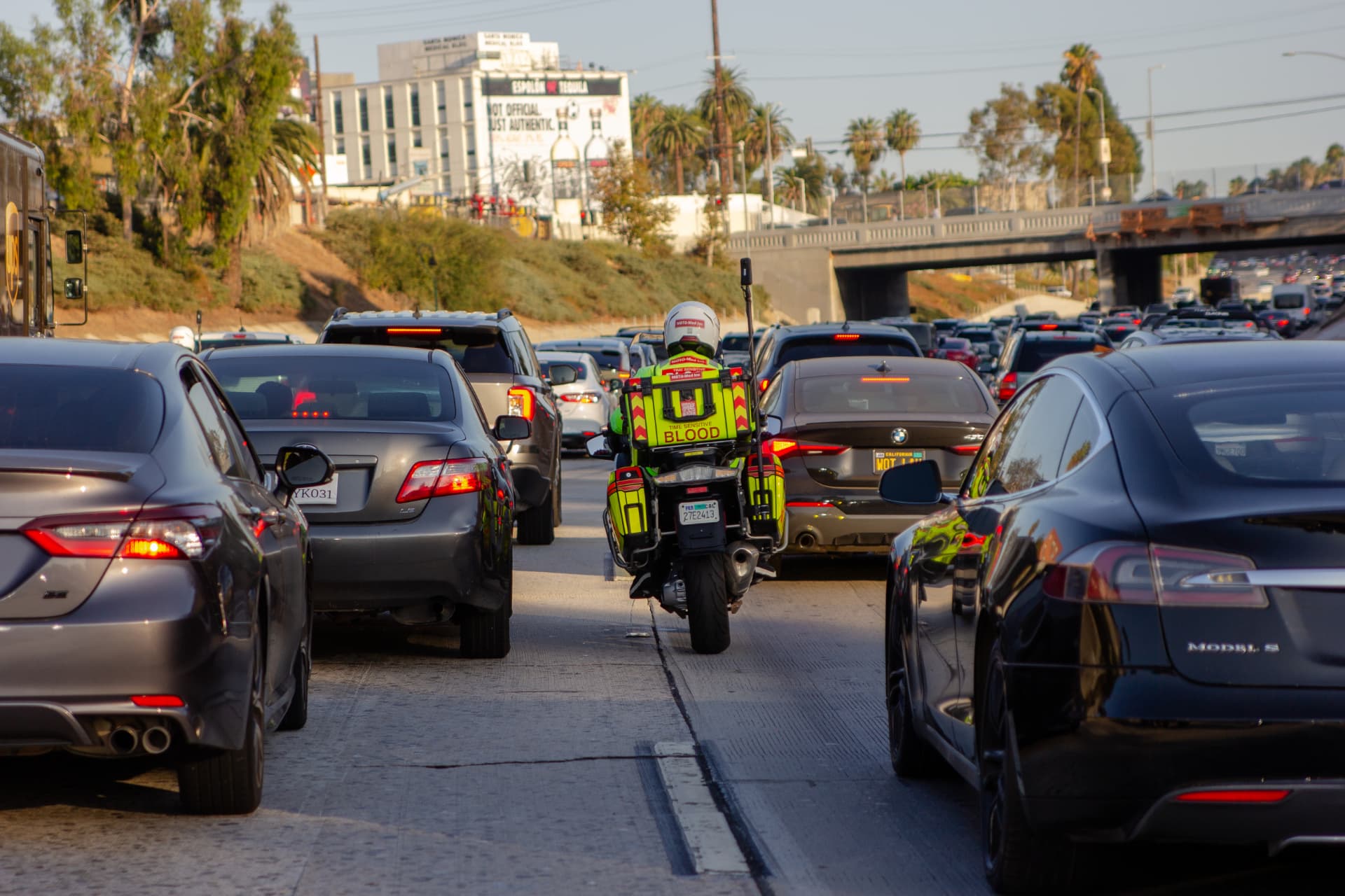 Moto-Med rider lane-splitting through heavy 101 freeway traffic in Los Angeles with a blood transport case