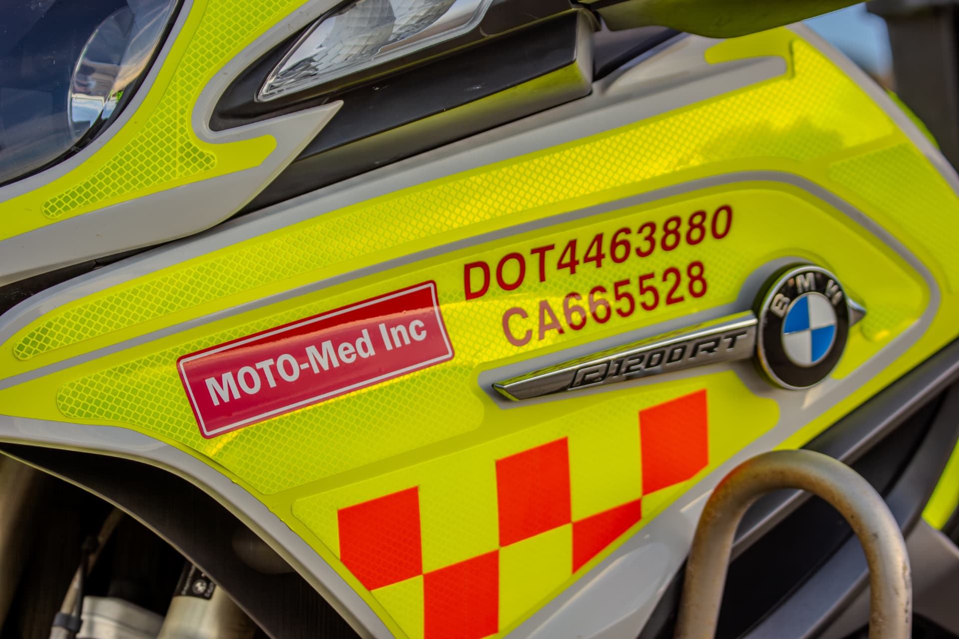 Close-up of a Moto-Med Inc. decal and DOT number on a hi-vis medical courier motorcycle