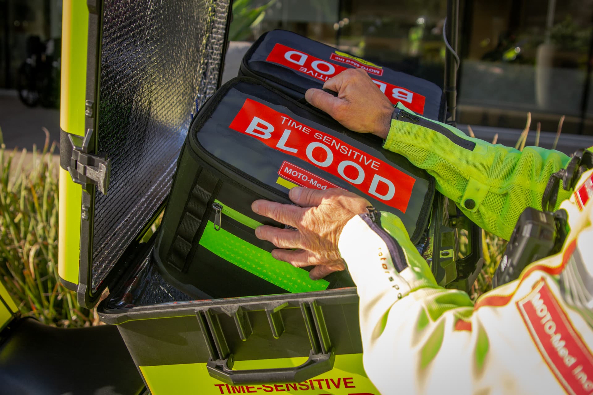 Moto-Med time-sensitive blood transport bag secured in a protective case by a rider in hi-vis gear